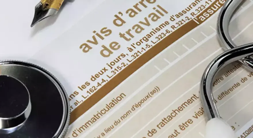 Un stéthoscope et un stylo sur un avis d'arrêt de travail, évoquant une maladie professionnelle pour une aide à domicile.