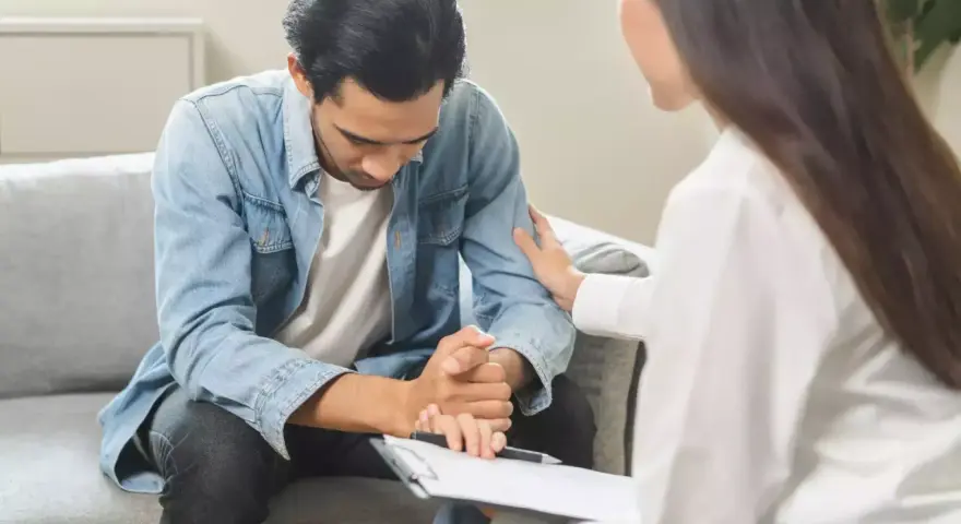 Un homme en arrêt maladie psychiatre reçoit un soutien réconfortant d'une thérapeute lors d'un contrôle.
