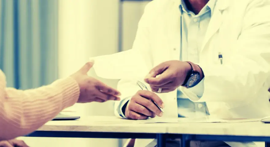 Un médecin remet un document, peut-être une suspension des indemnités journalières par le médecin conseil, à un patient.
