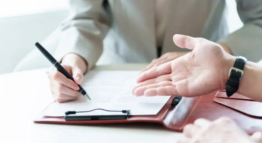 Une personne signe un contrat, discutant des conditions d'emploi avec un interlocuteur.