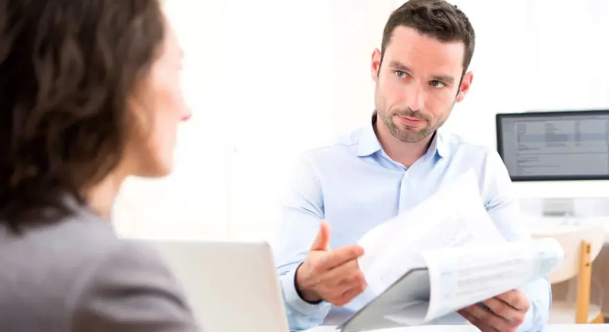Un homme explique un document à une femme, discutant peut-être de la VAE et de l'obligation employeur.