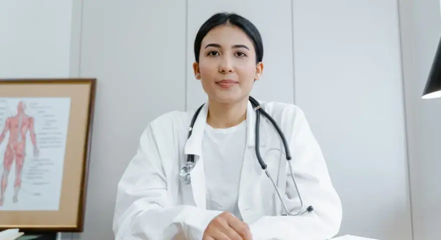 Médecine du travail : ce qu'il ne faut pas dire. Une doctoresse au regard bienveillant, stéthoscope autour du cou, devant un schéma anatomique.