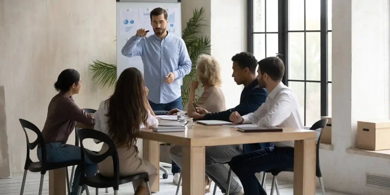 Un formateur explique des graphiques à une équipe. La formation des salariés est une obligation pour l'employeur.