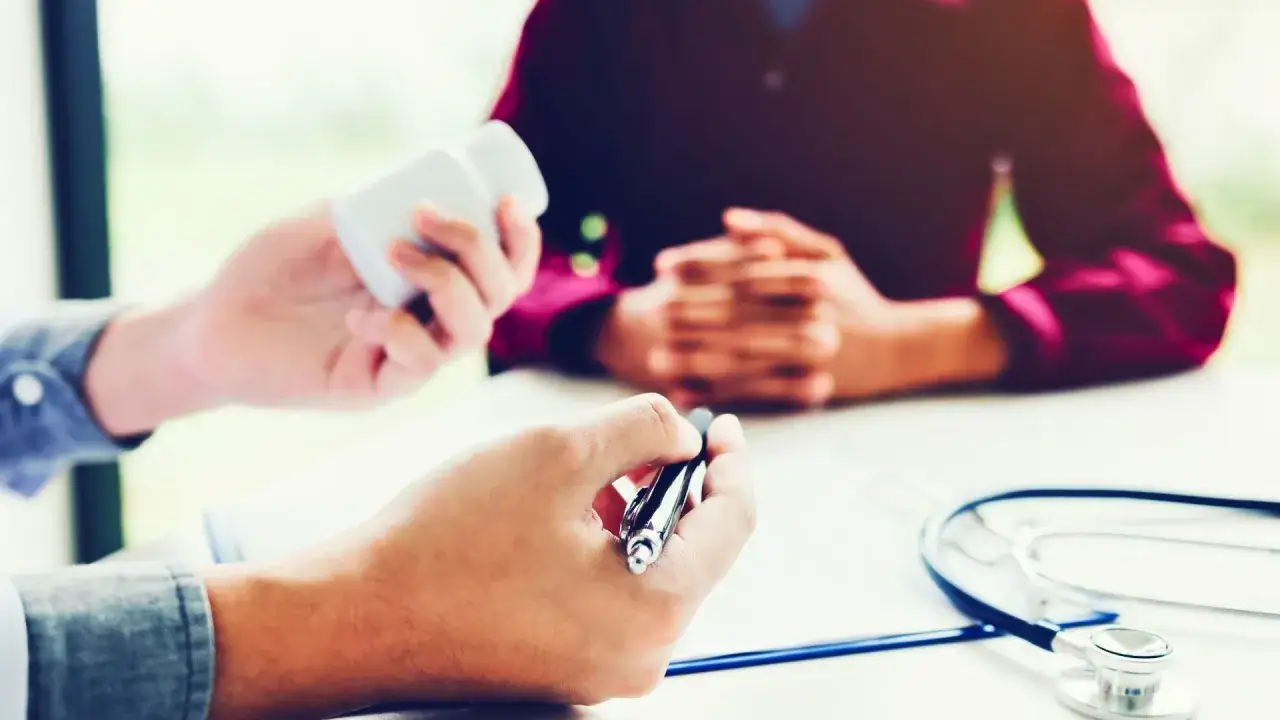 Consultation médicale pour une visite de reprise après inaptitude. Le médecin tient une ordonnance et un flacon de médicaments.