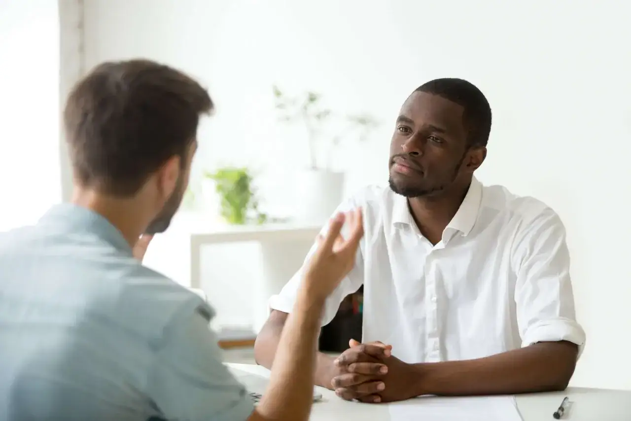Un homme écoute attentivement lors d'un rendez-vous de liaison, un échange de questions-réponses en cours.