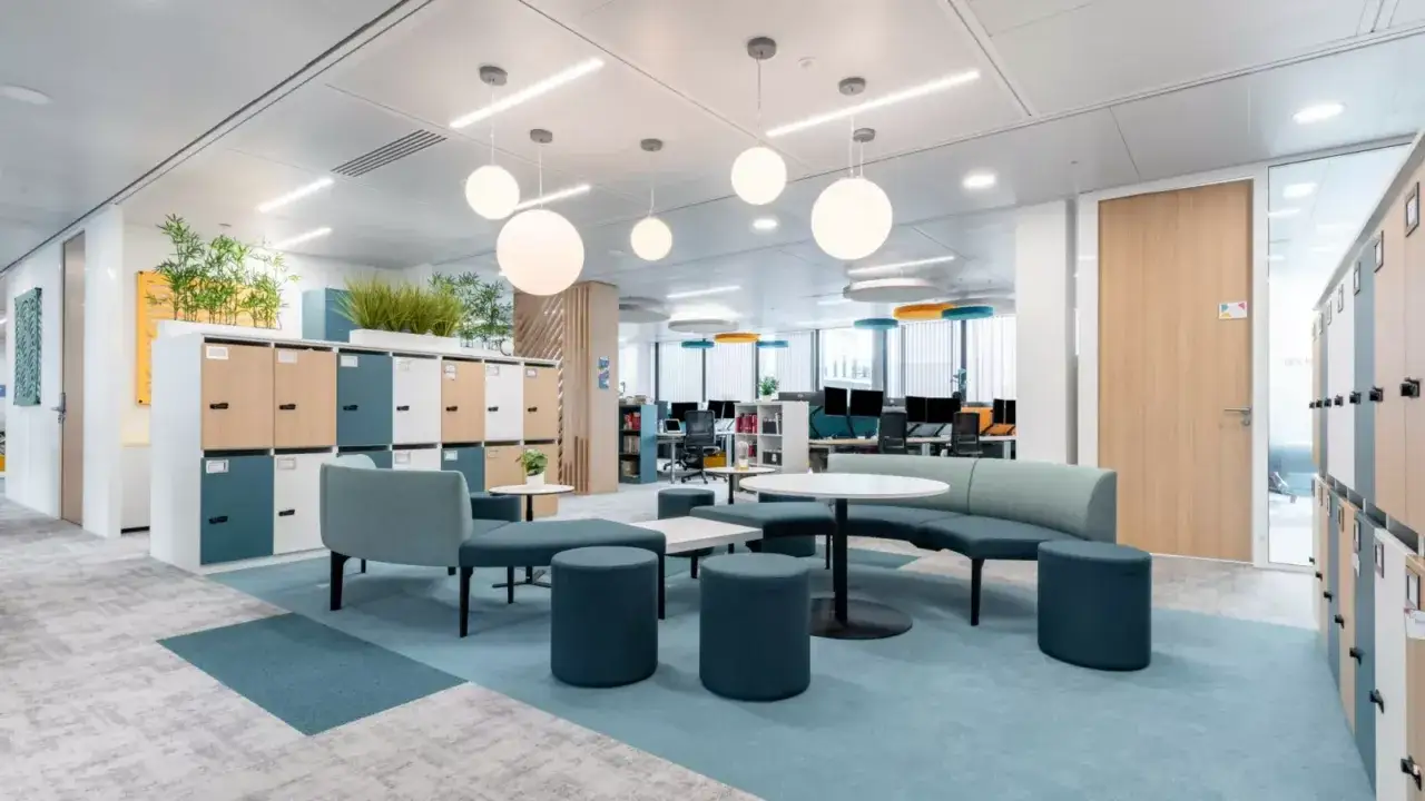Espace de travail moderne et lumineux, typique d'un flex office, avec des casiers, des sièges modulables et des tables basses.