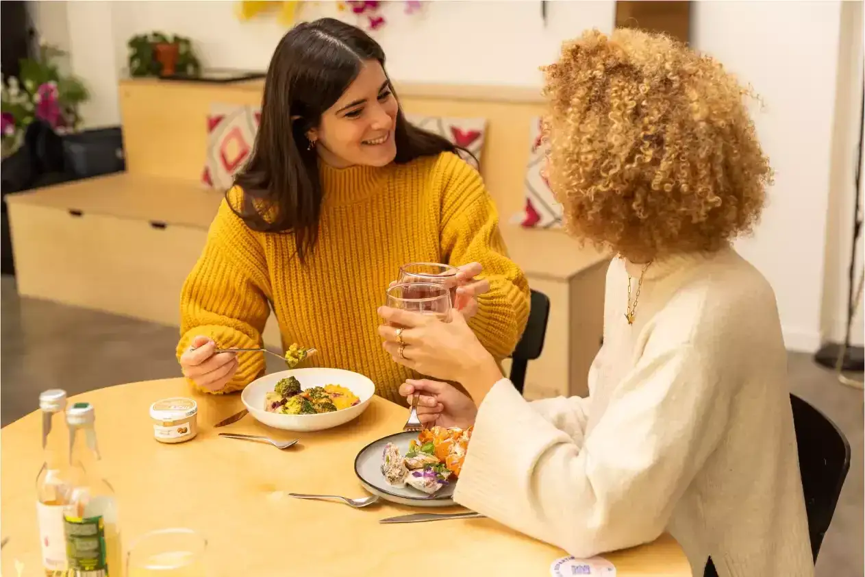 Deux amies profitent d'un pause déjeuner convivial, partageant un repas sain et des boissons.