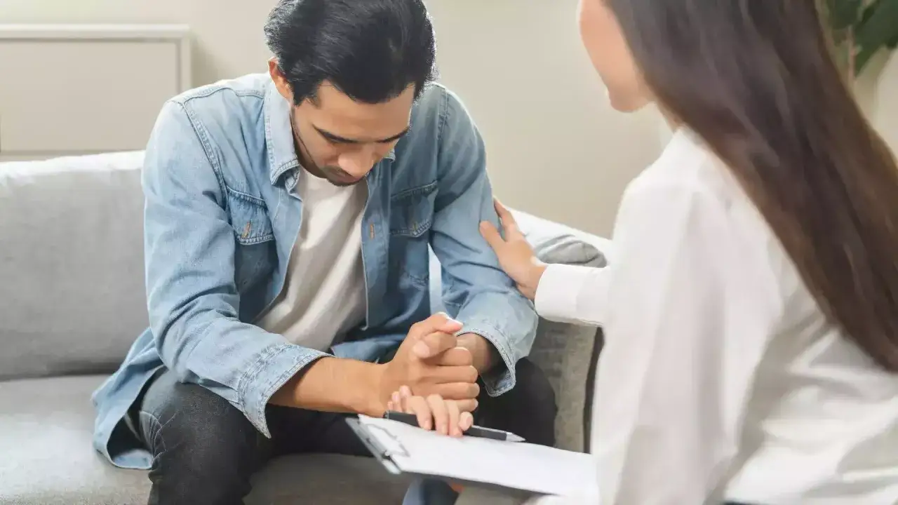 Un homme en arrêt maladie psychiatre reçoit un soutien réconfortant d'une thérapeute lors d'un contrôle.